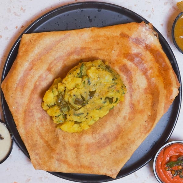 A golden-brown dosa filled with potato and spinach masala, served with chutneys.